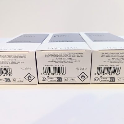 Three product boxes with barcodes and hazard symbols are displayed in a row on a white surface.