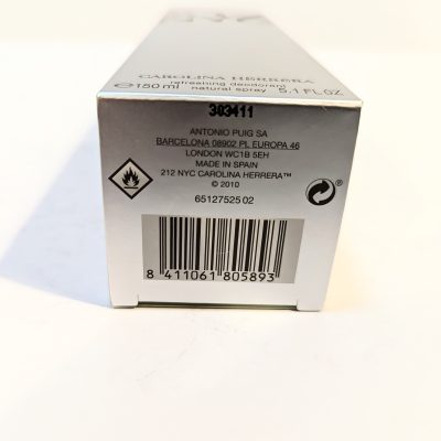 Close-up of the bottom of a product box with barcode, various product details, recycling symbol, hazard symbol, and text indicating the product is from Carolina Herrera made in Spain.