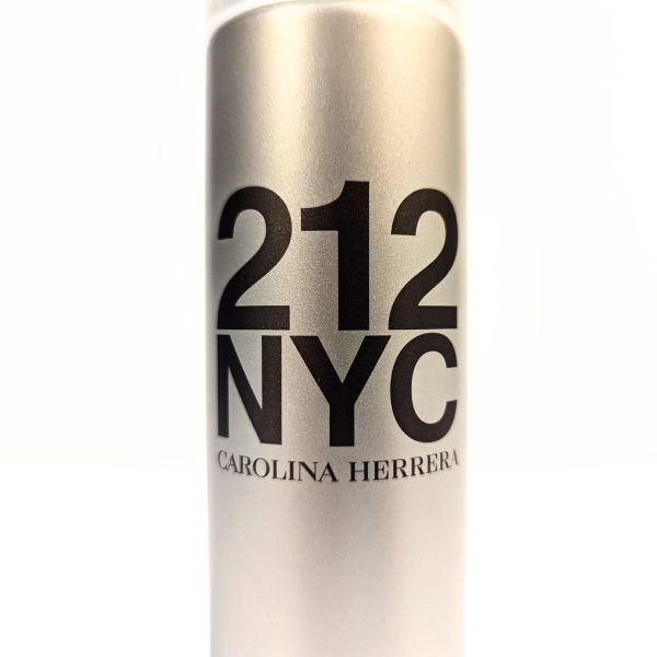 Close-up of a cylindrical bottle labeled "212 NYC Carolina Herrera" with a metallic finish.