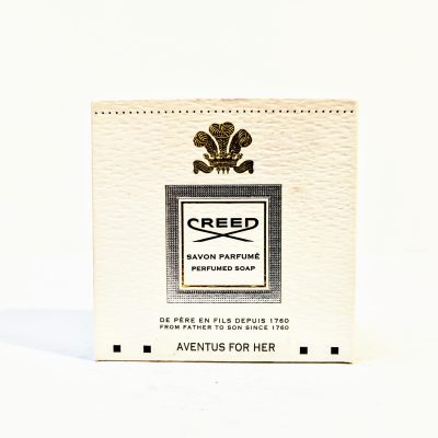 Image of a white box of Creed Aventus for Her perfumed soap, featuring the brand's logo and text "Savon Parfumé" in French and English, with a gold emblem and text indicating the brand's establishment in 1760.