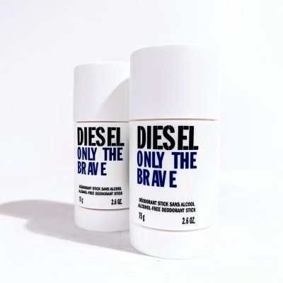 Two white deodorant sticks labeled "DIESEL ONLY THE BRAVE" with blue and black text stand against a plain white background. Each container is 75g (2.6 oz).