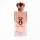 A clear glass bottle of Dolce & Gabbana perfume with a pink liquid inside, featuring a crown-shaped red and gold cap and the letter "Q" on the front.
