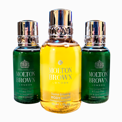 Three Molton Brown London bottles are displayed; two green bottles labeled “Bath & Shower” and a central yellow bottle labeled “Suma Ginseng Body Wash.” All bottles have shiny metallic caps.