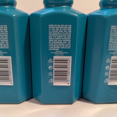 Three blue bottles with white labels displaying text, including ingredients, a barcode, recycle symbols, and a website URL. The bottles have octagonal shapes and the number 4711 embossed near the bottom.