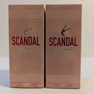 Two boxed bottles of "Scandal" by Jean Paul Gaultier shower gel, each with a capacity of 200 ml, side by side. The boxes are beige with red and gold text.