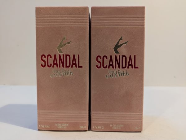 Two boxed bottles of "Scandal" by Jean Paul Gaultier shower gel, each with a capacity of 200 ml, side by side. The boxes are beige with red and gold text.