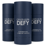 Three Calvin Klein Defy Deodorant Sticks for Men, 75ml each, in navy blue packaging are shown with one fully visible in front and the others behind. Labels display "Alcohol Free.