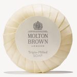 Round Molton Brown triple-milled milk soap wrapped in cream paper featuring a logo and text, available as 5x 25g miniatures.