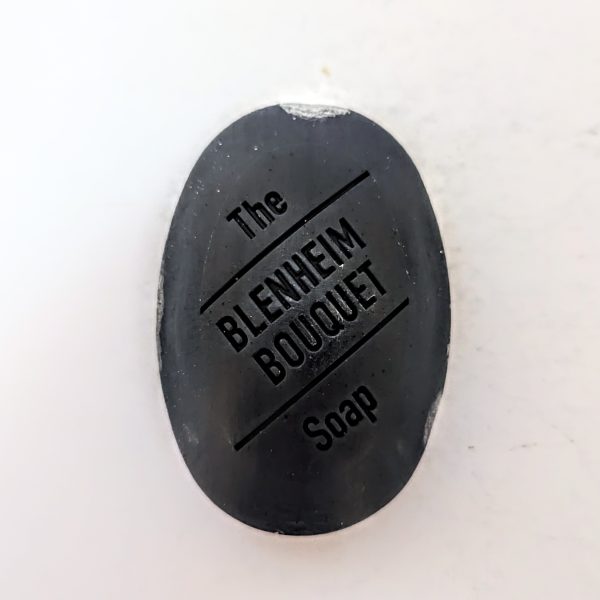 An oval black soap bar with "The Blenheim Bouquet Soap" engraved on its surface.