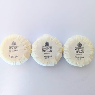 Three wrapped bars of Molton Brown London triple-milled soap are arranged side by side on a plain white surface.