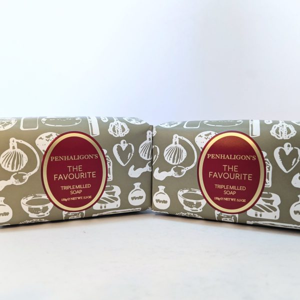 Two bars of Penhaligon's The Favourite triple-milled soap, each wrapped in grey paper with white illustrations and a red oval label, placed side by side on a white surface.
