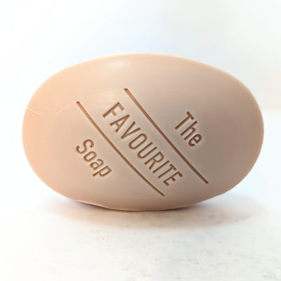 A beige oval bar of soap with the words “The FAVOURITE Soap” engraved on its surface, placed on a white background.