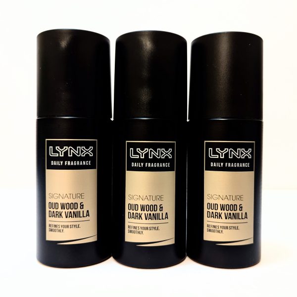Three black cans of Lynx Daily Fragrance Signature Oud Wood & Dark Vanilla are standing side by side on a white surface.