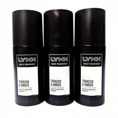 Three black cans of Lynx Daily Fragrance in the Tobacco & Amber scent are arranged side by side against a white background.
