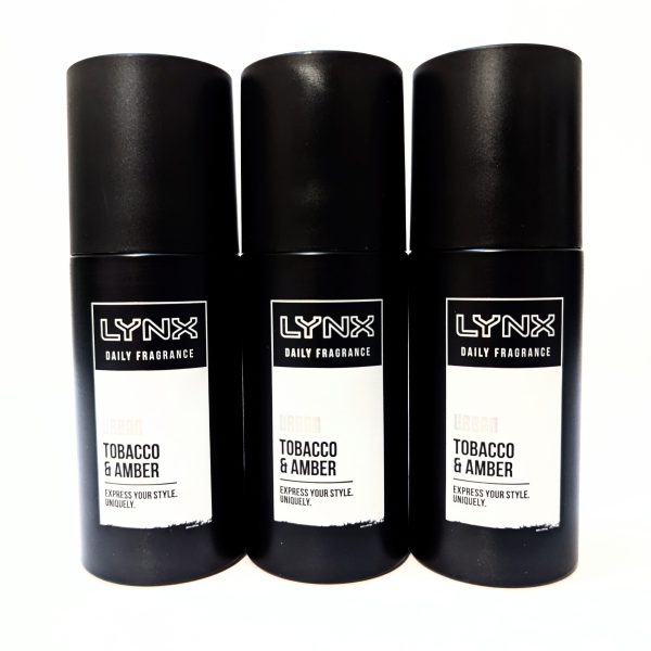 Three black cans of Lynx Daily Fragrance in the Tobacco & Amber scent are arranged side by side against a white background. Three black cans of Lynx Daily Fragrance in the Tobacco & Amber scent are arranged side by side against a white background.