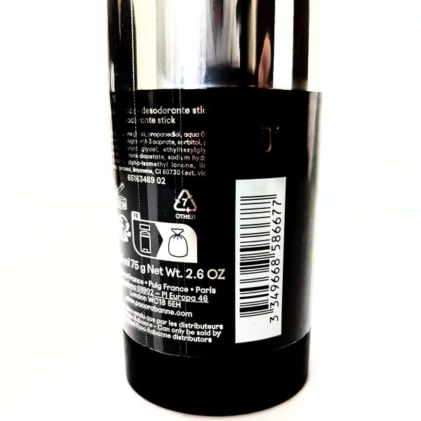 A close-up of a black deodorant stick showing product information, recycling symbols, a barcode, and a net weight of 2.6 oz on the label.