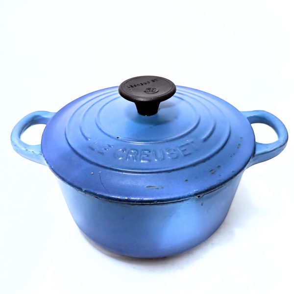 A blue Le Creuset cast iron Dutch oven with a black knob and two handles, shown on a white background.