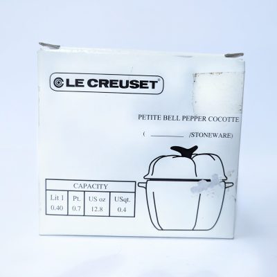 White box packaging for a Le Creuset petite bell pepper cocotte, with product illustration and capacity details listed in liters, pints, ounces, and quarts.