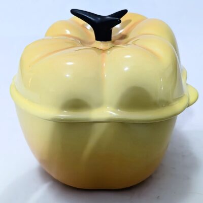 A yellow ceramic casserole dish shaped like a pumpkin, with a lid featuring a black stem-shaped handle.