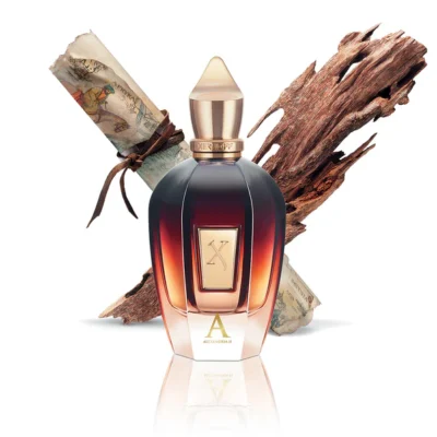 The Xerjoff Alexandria II EDP Spray (100ml, Unisex) with a gold cap is displayed before a rolled parchment and aromatic wood on a white background.