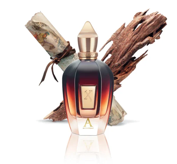 The Xerjoff Alexandria II EDP Spray (100ml, Unisex) with a gold cap is displayed before a rolled parchment and aromatic wood on a white background.