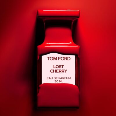 A Tom Ford Lost Cherry Eau de Parfum 50ml Spray bottle, partly covered in glossy red liquid, sits against a vibrant red background.