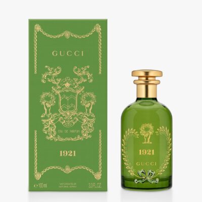 A green bottle of Gucci 1921 Eau de Parfum Spray, Unisex, 100ml is shown beside its decorative matching green and gold box.