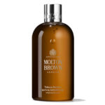 A bottle of Molton Brown London Tobacco Absolute Bath & Shower Gel with a brown body and silver cap, shown against a white background.