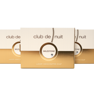 Three boxes of Club de Nuit Milestone luxury handcrafted soap with gold and white packaging are displayed against a white background.