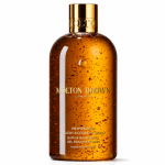 The Molton Brown Mesmerising Oudh Accord & Gold Bath & Shower Gel, 300ml, comes in a clear bottle with visible gold flakes, a gold cap, and gold text on the label.