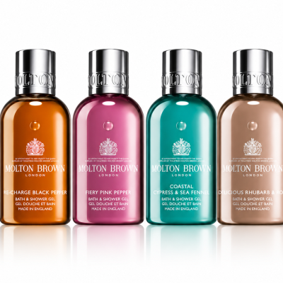 The Molton Brown Woody & Floral Body Care Shower Gel Collection (4x 100ml) features four bottles in a row, each with a unique color and label: black pepper, pink pepper, cypress & sea fennel, and rhubarb & rose.