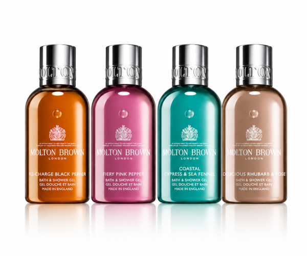 The Molton Brown Woody & Floral Body Care Shower Gel Collection (4x 100ml) features four bottles in a row, each with a unique color and label: black pepper, pink pepper, cypress & sea fennel, and rhubarb & rose.