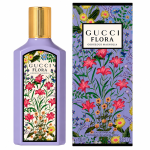 A bottle and box of Gucci Flora Gorgeous Magnolia perfume, both featuring a colorful floral design with pink, yellow, and blue flowers on a light purple background.