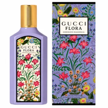 A bottle and box of Gucci Flora Gorgeous Magnolia perfume, both featuring a colorful floral design with pink, yellow, and blue flowers on a light purple background.
