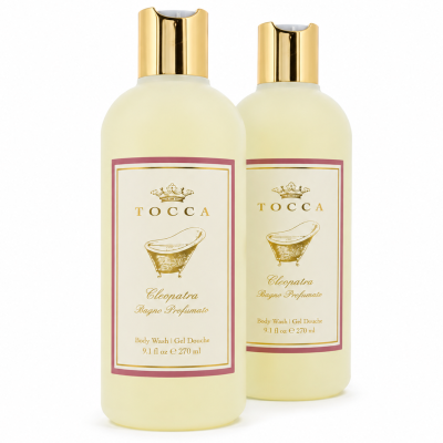 Two bottles of Tocca Cleopatra body wash, each with gold caps, cream-colored liquid, and a label featuring a gold motif and product details.
