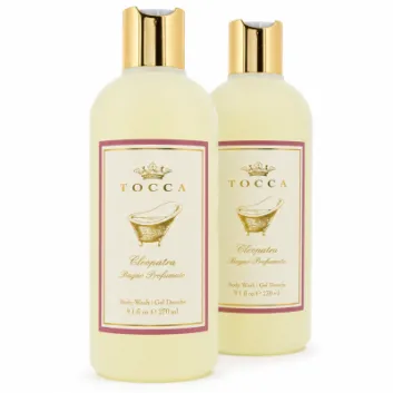Two bottles of Tocca Cleopatra body wash, each with gold caps, cream-colored liquid, and a label featuring a gold motif and product details.
