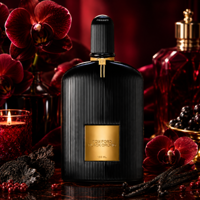 A bottle of Tom Ford Black Orchid Eau de Parfum Spray, Unisex, 100ml, with a gold label is surrounded by red candles, dark orchids, and decorative glassware on a dark, elegant surface.