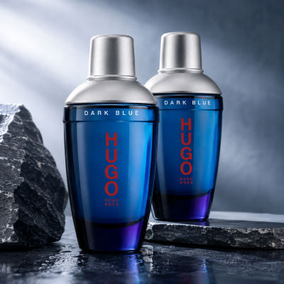Two bottles of 2x Hugo Boss Dark Blue EDT for Men, 75ml Spray, stand on a dark surface beside rocks, set against a cool blue-gray background.