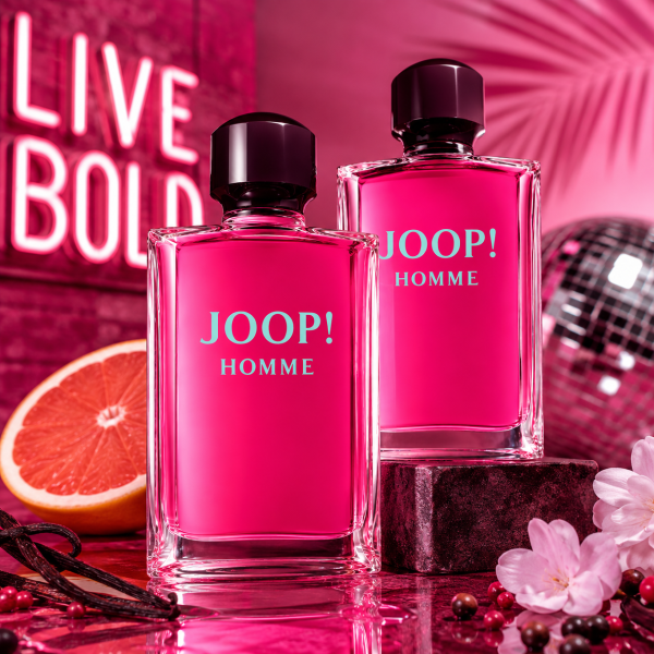 Two bottles of Joop! Homme Eau de Toilette for Men (200ml each) are displayed on a vibrant pink background, accompanied by a neon “LIVE BOLD” sign, a grapefruit slice, disco ball, flowers, and peppercorns.