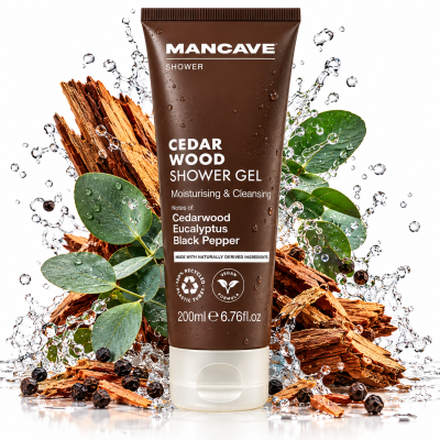 3x ManCave Cedarwood Shower Gel, Man Cave, 200ml stands upright among cedarwood, eucalyptus leaves, and black peppercorns. The tube highlights moisturising and cleansing benefits.