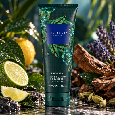 3x Ted Baker Fusion Enigmatic Body & Hair Wash, 250ml tubes, displayed on a wet natural surface and surrounded by lime, lemon, lavender, green leaves, and cardamom pods.