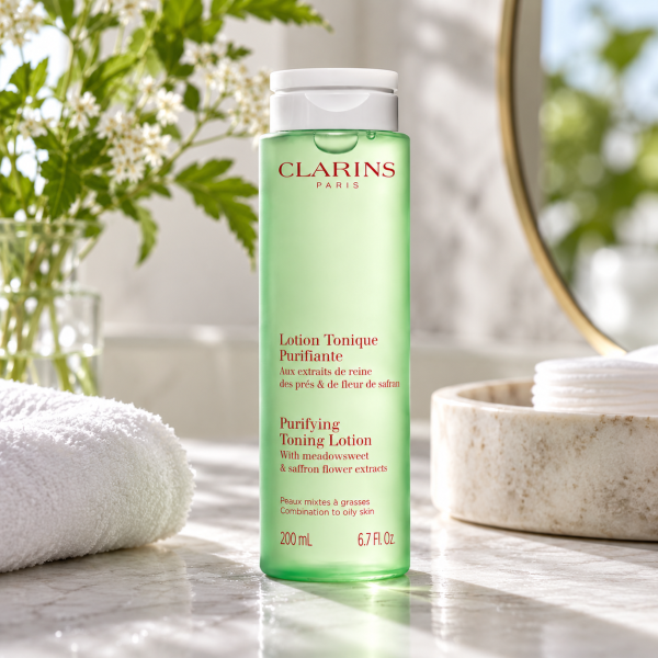 A translucent green bottle of 3x Clarins Purifying Toning Face Lotion 200ml with a white cap, standing on a marble countertop.