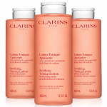 Three identical 400ml bottles of peach-colored Clarins Soothing Toning Face Lotion for very dry or sensitive skin.