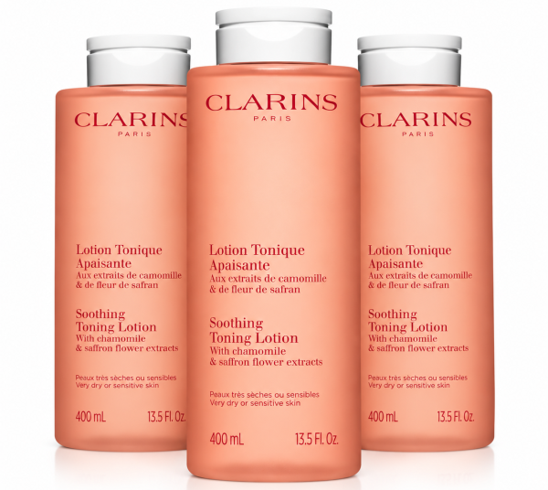 Three identical 400ml bottles of peach-colored Clarins Soothing Toning Face Lotion for very dry or sensitive skin.