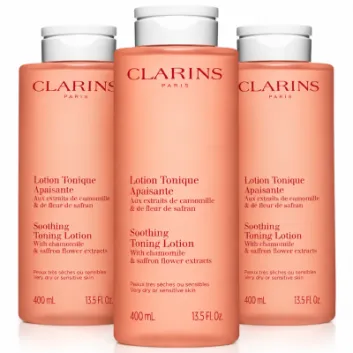 Three identical 400ml bottles of peach-colored Clarins Soothing Toning Face Lotion for very dry or sensitive skin.